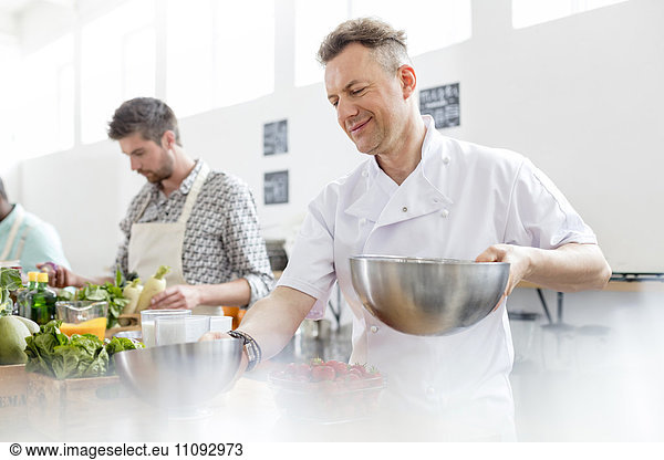 Chef teacher holding bowls in cooking class kitchen