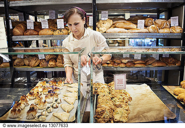 Chefkoch arrangiert Backwaren in Vitrine in Bäckerei