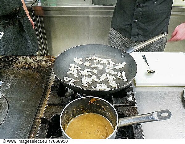 Chefkoch kocht flambierten atlantischen Tintenfisch in einer großen Pfanne in einer professionellen Küche. Schritt für Schritt Gourmet Meeresfrüchte Rezept. Professionelle Gourmet-Küche Konzept