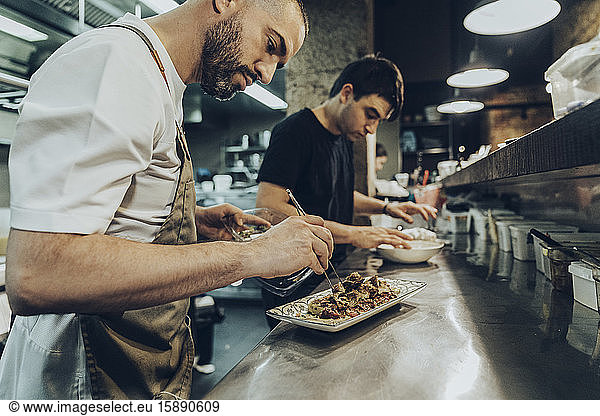 chefs in restaurant arranging food on plates for serving