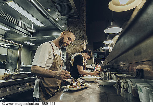 chefs in restaurant arranging food on plates for serving