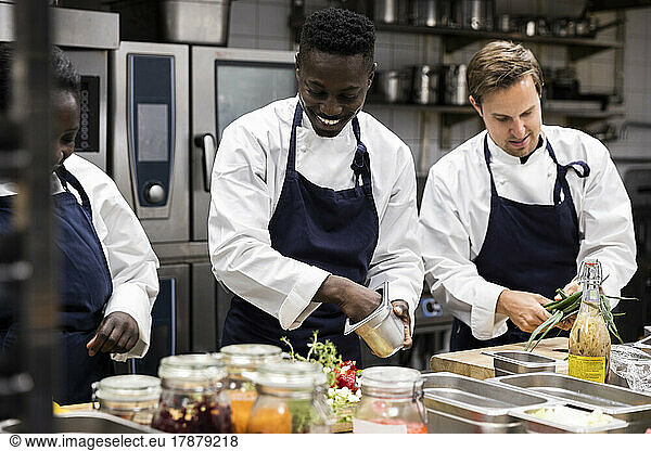 Chefs talking while preparing food in restaurant kitchen
