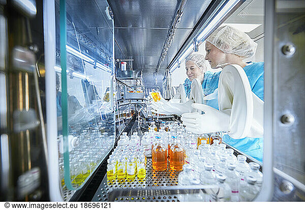 Chemical workers passing chemical bottles inside microbiological safety cabinet