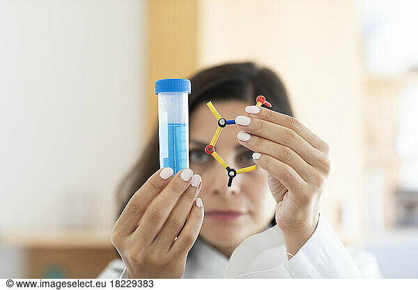 Chemist holding test tube and molecular model  focus on foreground
