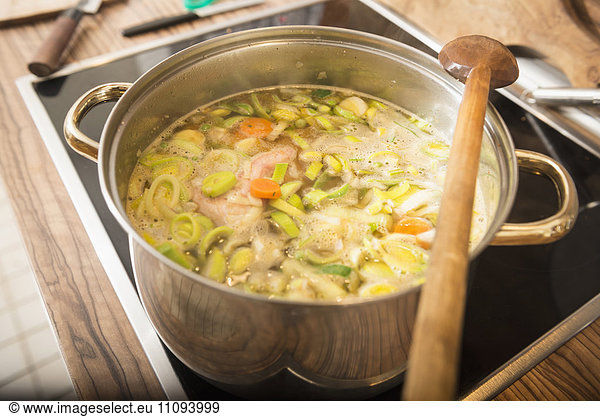 Chicken soup boiling with leek and carrot in a pot on stove