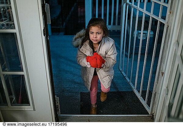 Child coming inside in evening after playing in cold weather