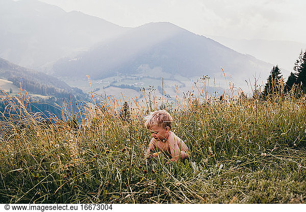Child hiding in the grass in the mountains in summer