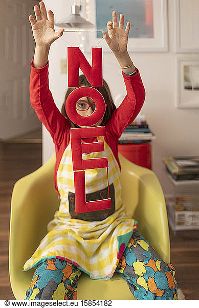 Child holding Noel Banner at home