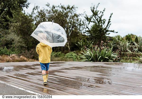 Child in yellow rain jacket holding an umbrella