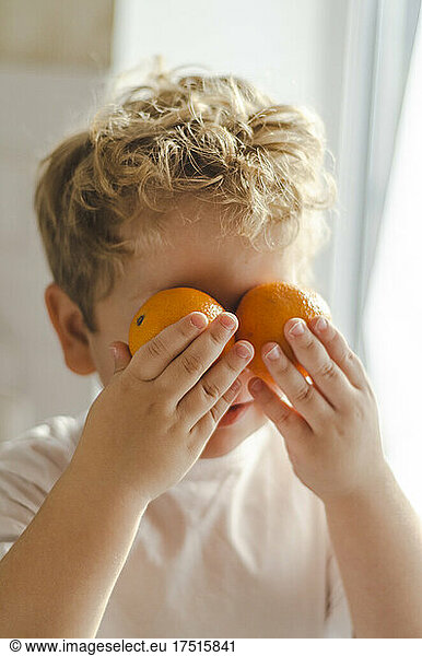 child leaned tangerines to his eyes