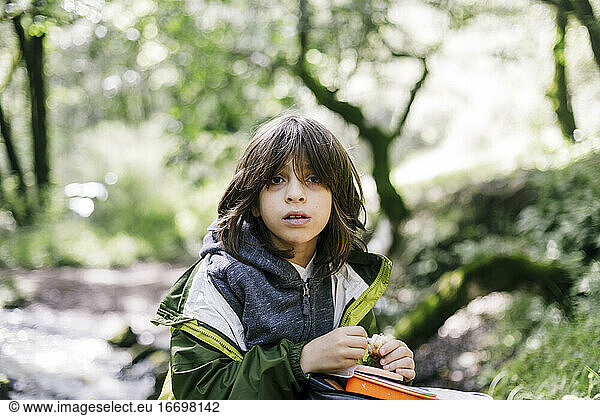 Child looking away while eating during hiking by forest