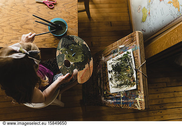 Child Paints with palette and easel from above