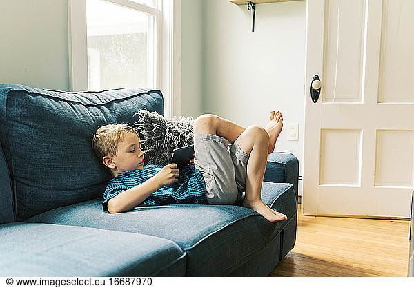 child playing with a tablet on the sofa