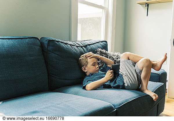 child playing with a tablet on the sofa