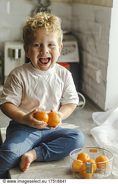 child rejoice at tangerines in hands