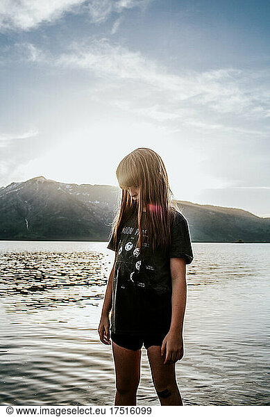 Child standing in lake in front of snowy mountain