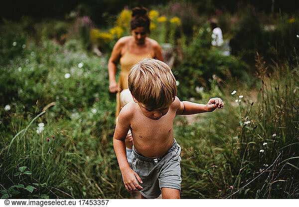 Child walking among weeds with mom behind in a hot summer day