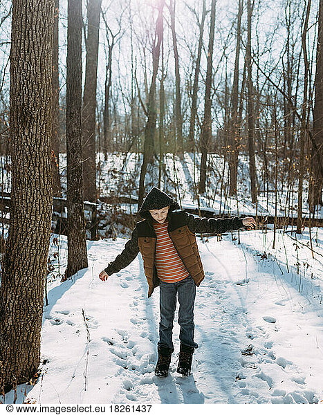 Child walking on snowy hiking trail in winter in forest