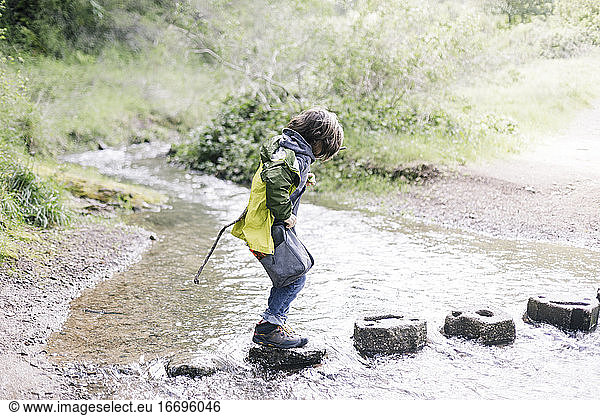 Child walking on stones crossing a river