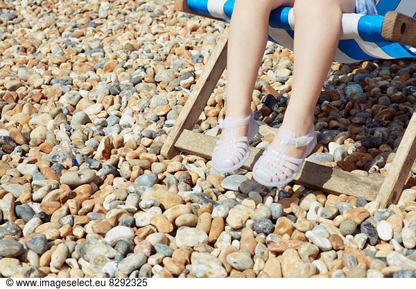 Child with plastic sandals on beach deck chair