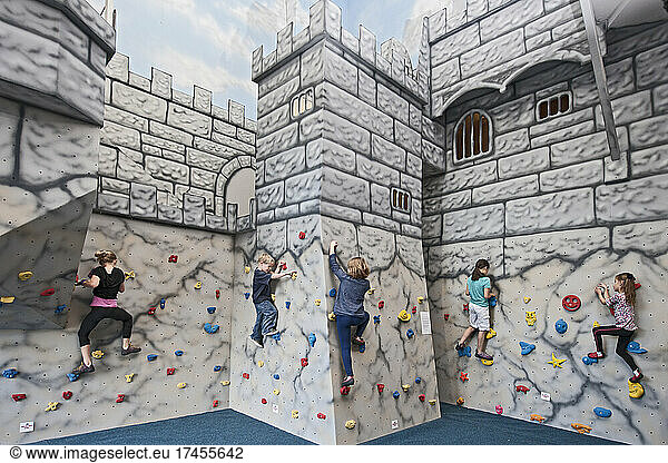children bouldering on castle like climbing wall