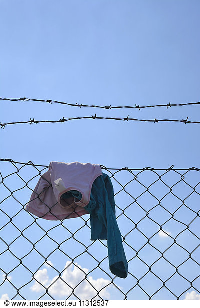 Children clothing hanging on wire mesh fence