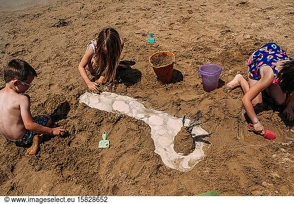 children digging in sand on a sunny day at the beach