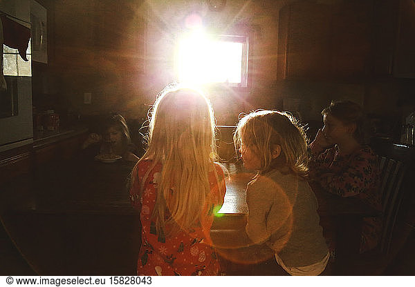 Children eating breakfast at table in morning sunflare