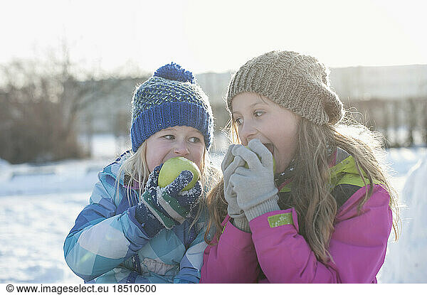 Children eating green apple on snow field