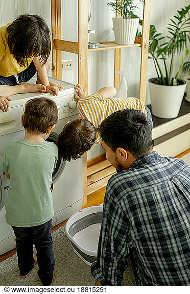 Children helping father washing clothes at home