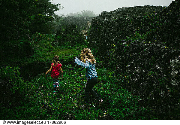 Children hike through green tropical forest with wall remains