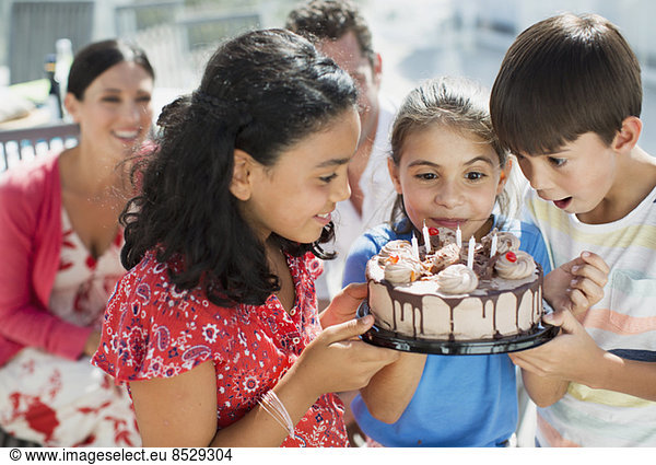 Children holding birthday cake outdoors