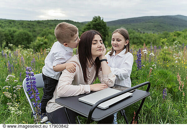 Children irritating freelancer at desk in lupine flowers