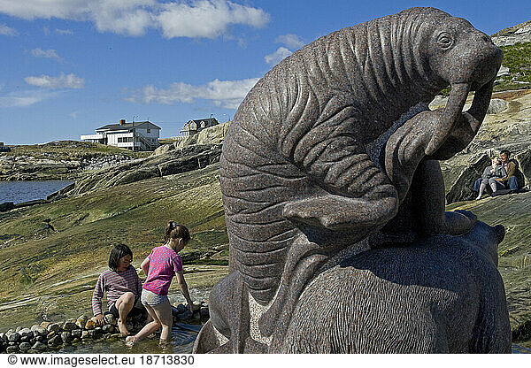 Children play in the water around a statue on a sunny day in Nuuk  Greenland.