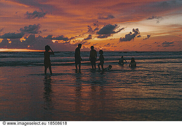 Children play on the beach near the ocean at sunset. Bali  Indonesia