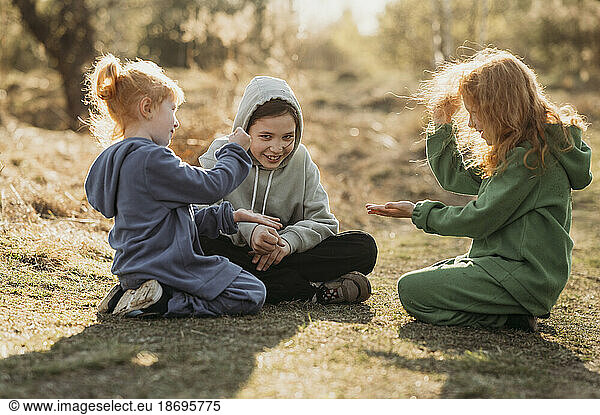 Children playing in clearing at forest on sunny day