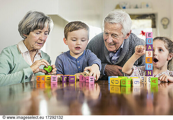 Children playing with toy blocks by grandparent at home