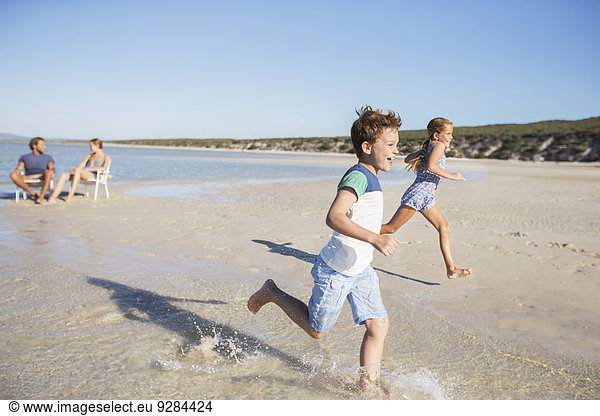 Children running in waves on beach