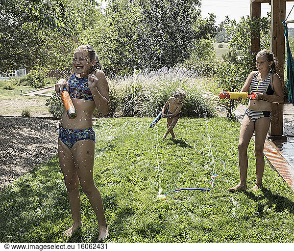 children spraying each other with water hose