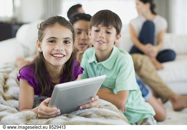 Children using digital tablet on sofa in living room