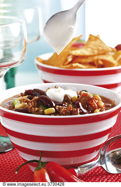 Chili con carne  minced meat  kidney beans  corn  bell pepper  chili  tortilla chips and creme fraiche