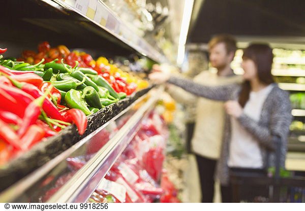 Chili-Paprika im Regal arrangiert mit paar Einkäufen im Hintergrund im Supermarkt