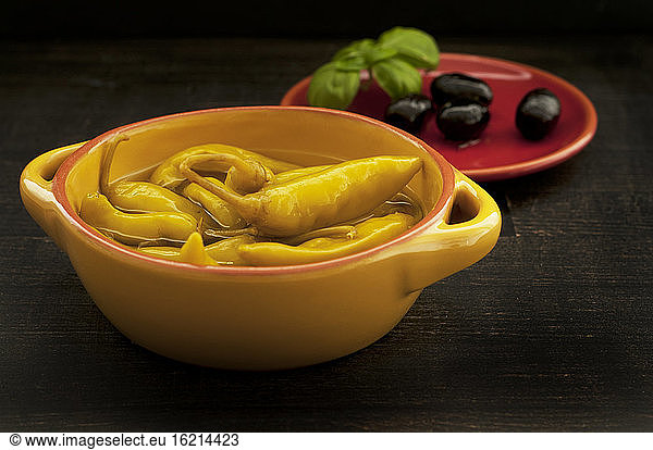 Chilis mit Oliven auf Holztisch  Nahaufnahme