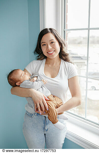 Chinese Asian mother holding newborn infant baby son. Happy family.
