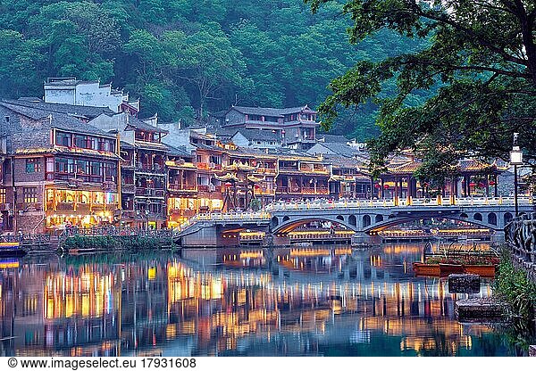 Chinesische Touristenattraktion  Feng Huang Ancient Town (Phoenix Ancient Town) am Fluss Tuo Jiang mit einer nachts beleuchteten Brücke. Provinz Hunan  China  Asien
