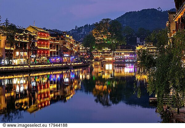 Chinesische Touristenattraktion  Feng Huang Ancient Town (Phoenix Ancient Town) am Fluss Tuo Jiang mit einer nachts beleuchteten Brücke. Provinz Hunan  China  Asien