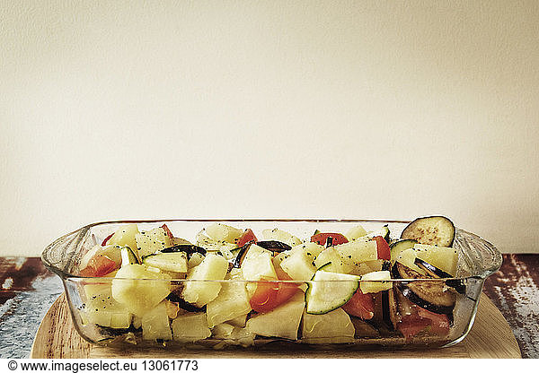 Chopped vegetables in serving dish on table against wall