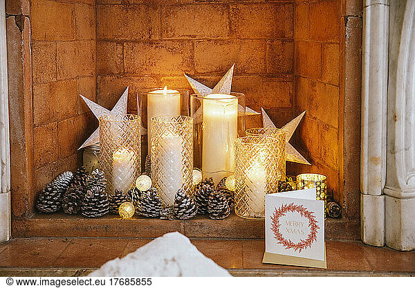 Christmas candles and greeting card inside brick fireplace
