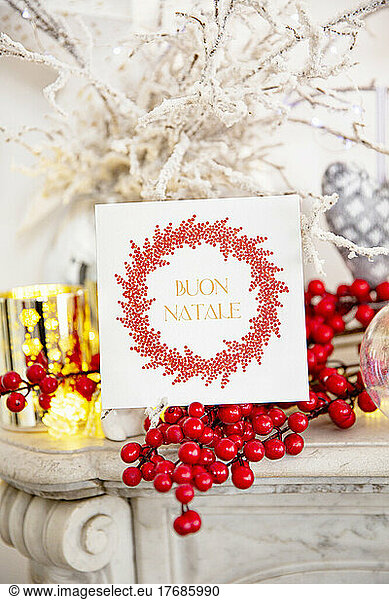 Christmas card and red Holly berries on marble fireplace