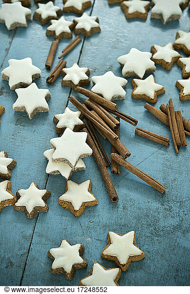Christmas cinnamon star shaped cookies and cinnamon on blue rustic wooden background